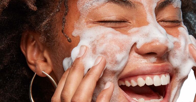 Frau mit schwarzer Haut wäscht ihr Gesicht mit Gesichtsschaum